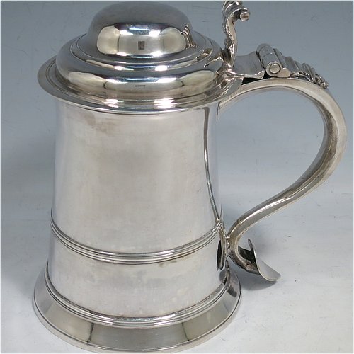 An Antique Georgian Sterling Silver lidded quart tankard, having a plain round straight-sided body, a hinged dome lid with cast scroll thumb-piece, a scroll handle with heart-shaped terminal, and sitting on a collet foot. Made by William Shaw & William Priest of London in 1758. The dimensions of this fine hand-made antique silver tankard are height 16.5 cms (6.75 inches), length 16.5 cms (6.5 inches), and it weighs approx. 620g (20 troy ounces).   