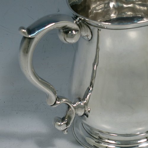 An Antique Georgian George II Sterling Silver three-quarter pint tankard or mug, having a plain round bellied body, a scroll handle, and sitting on a collet foot. Made by Robert Lucas of London in 1740. The dimensions of this fine hand-made antique silver three-quarter pint mug or tankard are height 11 cms (4.3 inches), diameter at top 7.5 cms (3 inches), and it weighs approx. 263g (8.5 troy ounces).    