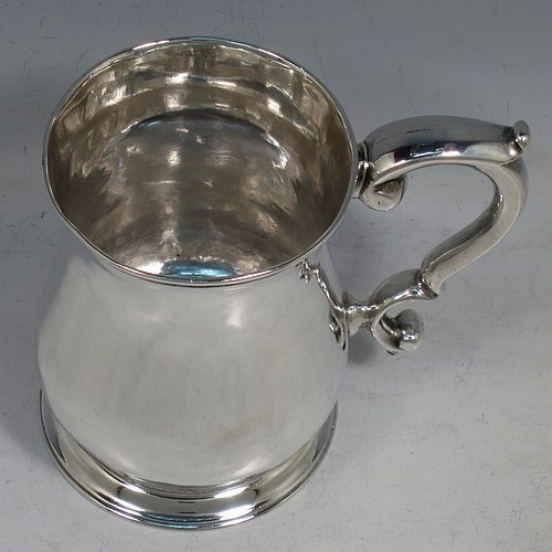 An Antique Georgian George II Sterling Silver three-quarter pint tankard or mug, having a plain round bellied body, a scroll handle, and sitting on a collet foot. Made by Robert Lucas of London in 1740. The dimensions of this fine hand-made antique silver three-quarter pint mug or tankard are height 11 cms (4.3 inches), diameter at top 7.5 cms (3 inches), and it weighs approx. 263g (8.5 troy ounces).    