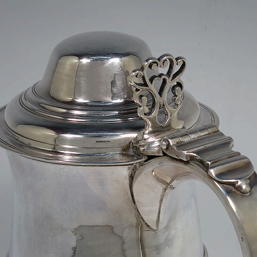 A very handsome Antique Georgian Sterling Silver lidded quart tankard, having a plain round bellied body with central reeded girdle, a hinged dome lid with hand-pierced thumb-piece, a scroll handle with heart-shaped terminal, and sitting on a pedestal foot. Made by Peter and Anne Bateman of London in 1795. The dimensions of this fine hand-made antique silver quart tankard are height 21 cms (8.25 inches), length 18 cms (7 inches), and it weighs approx. 767g (24.7 troy ounces).   