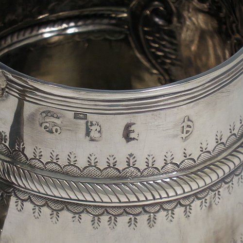 An Antique Queen Anne Sterling Silver half-pint mug / tankard, having a round straight-sided body, with reeded borders, hand-chased fluted and gadroon decoration, a scroll reeded handle, a vacant oval cartouche with scroll-work surround, and sitting on a collet foot. Made by John Cory of London in 1702. The dimensions of this fine hand-made antique silver tankard / mug are height 9 cms (3.5 inches), diameter at top 6.5 cms (2.5 inches), and it weighs approx. 116g (3.7 troy ounces).   