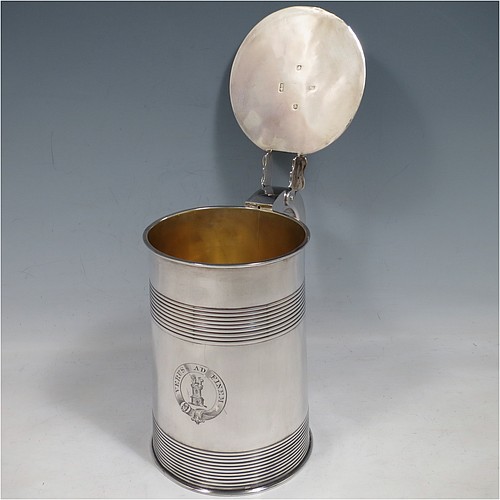 An Antique Georgian Sterling Silver lidded quart tankard, having a plain round straight-sided body with two bands of hand-chased reeded decoration, gold-gilt interior, a hinged flat lid with thumb-piece, a scroll handle, and sitting on a flat base. Made by Edward Fernell  of London in 1783. The dimensions of this fine hand-made antique silver tankard are height 16.5 cms (6.5 inches), length 17 cms (6.75 inches), and it weighs approx. 757g (24.4 troy ounces). Please note that this item is crested.   