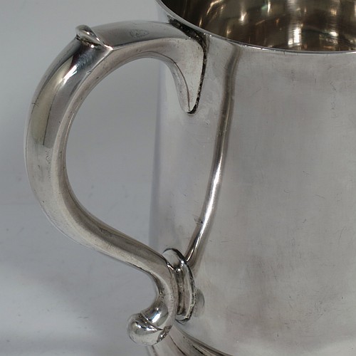 An Antique Georgian George II Sterling Silver pint tankard or mug, having a plain round bellied body, a scroll handle, and sitting on a collet foot. Made by Thomas Mason of London in 1733. The dimensions of this fine hand-made antique silver pint mug or tankard are height 11.5 cms (4.5 inches), diameter at top 9 cms (3.5 inches), and it weighs approx. 364g (11.7 troy ounces). Please note that this item shows fire-stain surrounding the hallmarks which is acceptable for a piece from this period.