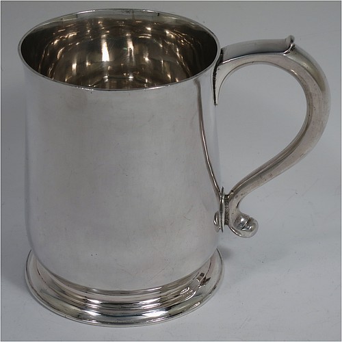 An Antique Georgian George II Sterling Silver pint tankard or mug, having a plain round bellied body, a scroll handle, and sitting on a collet foot. Made by Thomas Mason of London in 1733. The dimensions of this fine hand-made antique silver pint mug or tankard are height 11.5 cms (4.5 inches), diameter at top 9 cms (3.5 inches), and it weighs approx. 364g (11.7 troy ounces). Please note that this item shows fire-stain surrounding the hallmarks which is acceptable for a piece from this period.