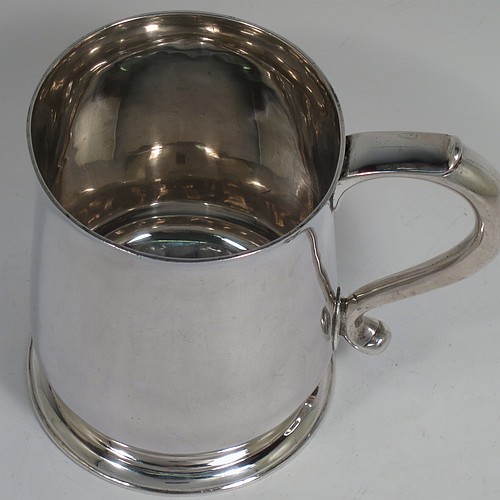 An Antique Georgian George II Sterling Silver pint tankard or mug, having a plain round bellied body, a scroll handle, and sitting on a collet foot. Made by Thomas Mason of London in 1733. The dimensions of this fine hand-made antique silver pint mug or tankard are height 11.5 cms (4.5 inches), diameter at top 9 cms (3.5 inches), and it weighs approx. 364g (11.7 troy ounces). Please note that this item shows fire-stain surrounding the hallmarks which is acceptable for a piece from this period.