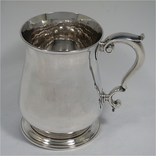 A very handsome and heavy Antique Georgian George II Sterling Silver pint tankard or mug, having a plain round bellied body, a scroll handle, and sitting on a collet foot. Made by Henry Brind of London in 1749. The dimensions of this fine hand-made antique silver pint mug or tankard are height 12.5 cms (5 inches), diameter at top 9 cms (3.5 inches), and it weighs approx. 377g (12.2 troy ounces).    