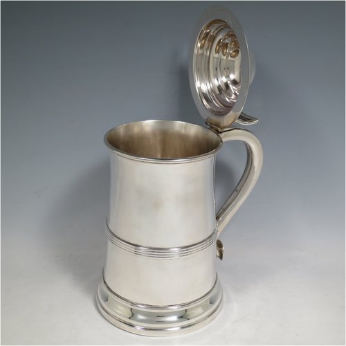 An Antique late Victorian Sterling Silver lidded quart tankard in a George I style, having a plain straight-sided body with an applied reeded band, a hinged dome lid with pierced thumb-piece, a scroll handle, and sitting on a reeded collet foot. Made by Elkington & Co., of Birmingham in 1900. The dimensions of this fine hand-made antique silver tankard are height 21.5 cms (8.5 inches), length 15 cms (6 inches), and it weighs approx. 682g (22 troy ounces).   