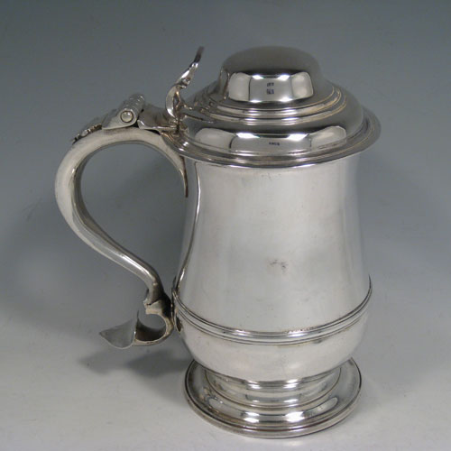 Antique Georgian sterling silver lidded quart tankard, having a plain bellied body, a hinged dome lid with thumb-piece, a scroll handle, sitting on a pedestal foot. Made by William Cripps of London in 1760. Weight approx. 758g (24.5 troy ounces). Please note that this piece has a small part-crest on the front of the body.