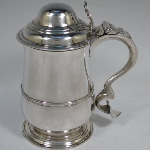 A very handsome Antique Georgian Sterling Silver lidded quart tankard, having a plain round bellied body with central reeded girdle, a hinged dome lid with hand-pierced thumb-piece, a scroll handle with heart-shaped terminal, and sitting on a pedestal foot. Made by James Young (overstriking another) of London in 1782. The dimensions of this fine hand-made antique silver quart tankard are height 19.5 cms (7.75 inches), length 17 cms (6.75 inches), and it weighs approx. 745g (24 troy ounces).    