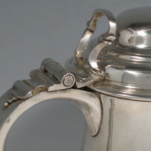 An Antique Georgian Sterling Silver lidded quart tankard, having a plain round bellied body, a hinged dome lid with thumb-piece, a scroll handle with heart-shaped terminal, sitting on a pedestal foot. Made by Whipham and Wright of London in 1760. The dimensions of this fine hand-made antique silver tankard are height 19 cms (7.5 inches), length 16 cms (6.25 inches), and it weighs approx. 723g (23 troy ounces).