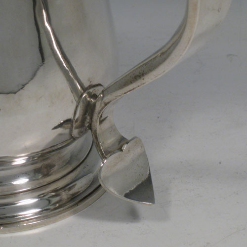 An Antique Georgian Sterling Silver lidded quart tankard, having a plain round bellied body, a hinged dome lid with thumb-piece, a scroll handle with heart-shaped terminal, sitting on a pedestal foot. Made by Whipham and Wright of London in 1760. The dimensions of this fine hand-made antique silver tankard are height 19 cms (7.5 inches), length 16 cms (6.25 inches), and it weighs approx. 723g (23 troy ounces).