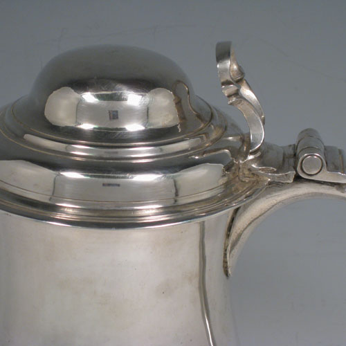 An Antique Georgian Sterling Silver lidded quart tankard, having a plain round bellied body, a hinged dome lid with thumb-piece, a scroll handle with heart-shaped terminal, sitting on a pedestal foot. Made by Whipham and Wright of London in 1760. The dimensions of this fine hand-made antique silver tankard are height 19 cms (7.5 inches), length 16 cms (6.25 inches), and it weighs approx. 723g (23 troy ounces).