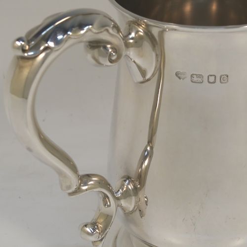 A very handsome Sterling Silver pint tankard or mug, having a plain round bellied body, a scroll handle with anthemion leaf thumb-piece, and sitting on a pedestal foot. This elegant sterling silver pint mug was made by Goldsmiths and Silversmiths of London in 1938. The dimensions of this fine hand-made silver pint tankard are height 14 cms (5.5 inches), diameter at top 8.5 cms (3.3 inches), and it weighs approx. 295g (9.5 troy ounces). Please note that the inside is finished off in a Butler finish which is not as bright as the outside.   