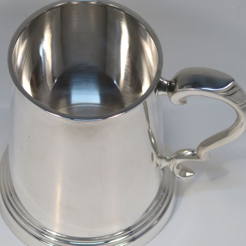 A very handsome Sterling Silver pint mug or tankard, in an early George I style, having a plain round straight-sided body with tapering sides, a scroll side-handle, and all sitting on a stepped collet foot. This elegant silver pint tankard or mug was made by Emile Viner of Sheffield in 1966. The dimensions of this fine hand-made silver tankard are height 12.5 cms (5 inches), diameter at top 8 cms (3.25 inches), and it weighs approx. 362g (11.7 troy ounces).   