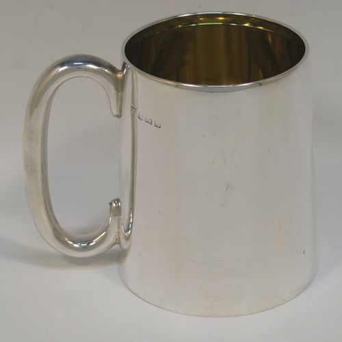 An elegant and heavy Sterling Silver pint mug or tankard having a plain round body with straight tapering sides, a plain loop side-handle, a gold-gilt interior, a hand-engraved spray of ivy and floral decoration on one side, and all sitting on a flat base. This beautiful silver tankard or mug was made by the Barker Brothers of Birmingham in 1930. The dimensions of this fine hand-made silver pint mug are height 11 cms (4.25 inches), diameter at top 8 cms (3 inches), and it weighs approx. 362g (11.7 troy ounces).   