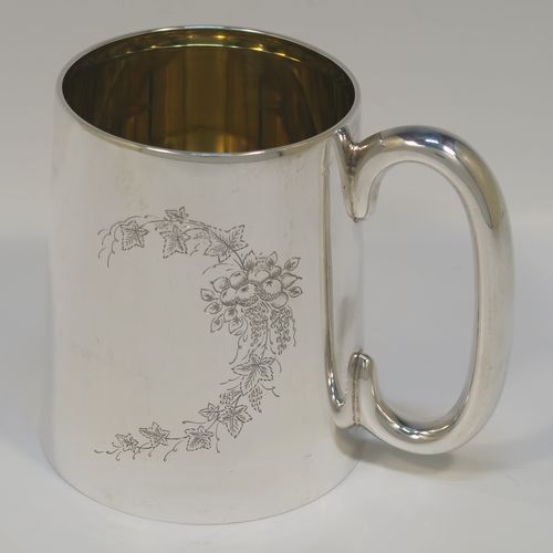 An elegant and heavy Sterling Silver pint mug or tankard having a plain round body with straight tapering sides, a plain loop side-handle, a gold-gilt interior, a hand-engraved spray of ivy and floral decoration on one side, and all sitting on a flat base. This beautiful silver tankard or mug was made by the Barker Brothers of Birmingham in 1930. The dimensions of this fine hand-made silver pint mug are height 11 cms (4.25 inches), diameter at top 8 cms (3 inches), and it weighs approx. 362g (11.7 troy ounces).   