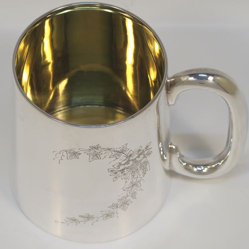 An elegant and heavy Sterling Silver pint mug or tankard having a plain round body with straight tapering sides, a plain loop side-handle, a gold-gilt interior, a hand-engraved spray of ivy and floral decoration on one side, and all sitting on a flat base. This beautiful silver tankard or mug was made by the Barker Brothers of Birmingham in 1930. The dimensions of this fine hand-made silver pint mug are height 11 cms (4.25 inches), diameter at top 8 cms (3 inches), and it weighs approx. 362g (11.7 troy ounces).   