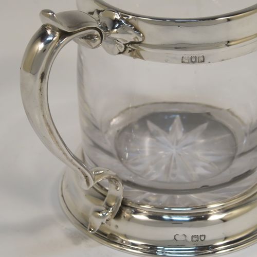 A handsome and unusual Antique Sterling Silver and glass pint tankard or mug, having a plain round hand-blown glass body with a star-cut base, together with silver mounts and a side scroll handle. This elegant silver and glass pint mug was made Carrington and Co., of London in 1915. The dimensions of this fine hand-made antique silver and glass pint mug or tankard are height 11.5 cms (4.5 inches), and diameter at top 8 cms (3 inches),   