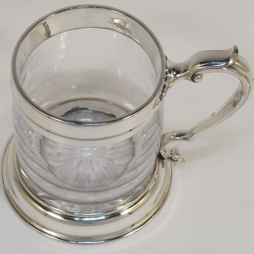 A handsome and unusual Antique Sterling Silver and glass pint tankard or mug, having a plain round hand-blown glass body with a star-cut base, together with silver mounts and a side scroll handle. This elegant silver and glass pint mug was made Carrington and Co., of London in 1915. The dimensions of this fine hand-made antique silver and glass pint mug or tankard are height 11.5 cms (4.5 inches), and diameter at top 8 cms (3 inches),   