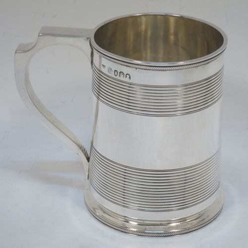 A very handsome Antique Georgian Sterling Silver pint tankard or mug, having a plain round straight-sided body with two bands of hand-chased reeded decoration and applied rope-twist top and bottom borders, a square cross-section scroll handle, and sitting on a flat base. Made by Solomon Royes of London in 1820. The dimensions of this fine hand-made antique silver mug or tankard are height 12 cms (4.75 inches), length 13 cms (5 inches), and it weighs approx. 324g (10.5 troy ounces).    