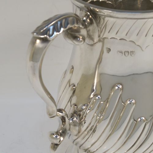 A handsome Antique Victorian Sterling Silver pint tankard or mug, having a round bellied body with hand-chased swirl-fluted decoration, a scroll side handle with an anthemion leaf thumb-piece, and sitting on a pedestal foot. This beautiful silver mug was made by Charles Stuart Harris of London in 1892. The dimensions of this fine hand-made antique silver pint mug or tankard are height 14 cms (5.5 inches), diameter at top 9 cms (3.5 inches), and it weighs approx. 372g (12 troy ounces).   