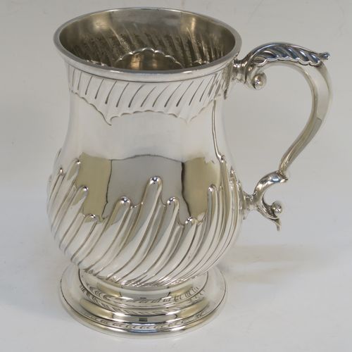 A handsome Antique Victorian Sterling Silver pint tankard or mug, having a round bellied body with hand-chased swirl-fluted decoration, a scroll side handle with an anthemion leaf thumb-piece, and sitting on a pedestal foot. This beautiful silver mug was made by Charles Stuart Harris of London in 1892. The dimensions of this fine hand-made antique silver pint mug or tankard are height 14 cms (5.5 inches), diameter at top 9 cms (3.5 inches), and it weighs approx. 372g (12 troy ounces).   