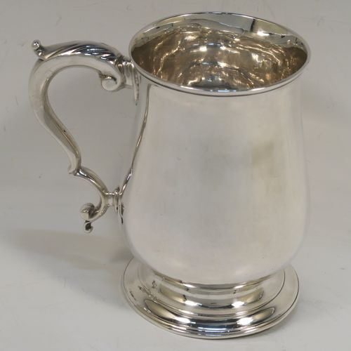 A very handsome Antique Georgian George III Sterling Silver pint tankard, having a plain round bellied body, a scroll handle with thumb-piece, and sitting on a pedestal foot. This elegant antique silver mug was made by Hester Bateman of London in 1786. The dimensions of this fine hand-made antique silver pint mug or tankard are height 12 cms (4.75 inches), diameter at top 8 cms (3 inches), and it weighs approx. 282g (9 troy ounces).   