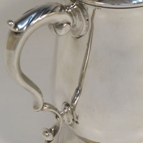 A very handsome Antique Georgian George III Sterling Silver pint tankard, having a plain round bellied body, a scroll handle with thumb-piece, and sitting on a pedestal foot. This elegant antique silver mug was made by Hester Bateman of London in 1786. The dimensions of this fine hand-made antique silver pint mug or tankard are height 12 cms (4.75 inches), diameter at top 8 cms (3 inches), and it weighs approx. 282g (9 troy ounces).   