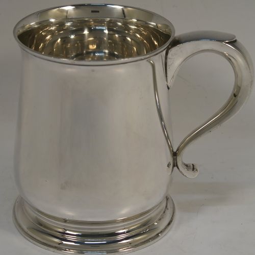 A heavy and very handsome Sterling Silver pint tankard or mug, having a plain round body with straight sides and a tucked under belly, a scroll side-handle, and sitting on a pedestal foot. This elegant silver pint mug was made by Goldsmiths and Silversmiths of London in 1928. The dimensions of this fine hand-made silver pint mug or tankard are height 11.5 cms (4.5 inches), diameter at top 8.5 cms (3.3 inches), and it weighs approx. 368g (11.9 troy ounces).   