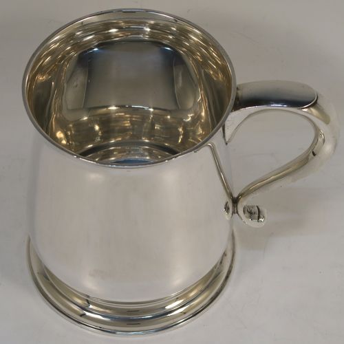 A heavy and very handsome Sterling Silver pint tankard or mug, having a plain round body with straight sides and a tucked under belly, a scroll side-handle, and sitting on a pedestal foot. This elegant silver pint mug was made by Goldsmiths and Silversmiths of London in 1928. The dimensions of this fine hand-made silver pint mug or tankard are height 11.5 cms (4.5 inches), diameter at top 8.5 cms (3.3 inches), and it weighs approx. 368g (11.9 troy ounces).   