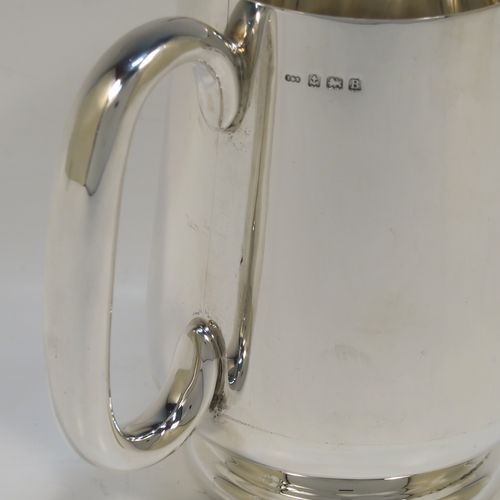 A very handsome Sterling Silver pint mug or tankard, having a plain round body with straight tapering sides and a tucked under belly, a plain loop side-handle, and all sitting on a pedestal foot. This elegant silver tankard or mug was made by Turner and Simpson of Birmingham in 1926. The dimensions of this fine hand-made silver pint mug are height 12 cms (4.75 inches), diameter at top 8 cms (3 inches), and it weighs approx. 288g (9.3 troy ounces).   