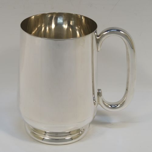 A very handsome Sterling Silver pint mug or tankard, having a plain round body with straight tapering sides and a tucked under belly, a plain loop side-handle, and all sitting on a pedestal foot. This elegant silver tankard or mug was made by Turner and Simpson of Birmingham in 1926. The dimensions of this fine hand-made silver pint mug are height 12 cms (4.75 inches), diameter at top 8 cms (3 inches), and it weighs approx. 288g (9.3 troy ounces).   