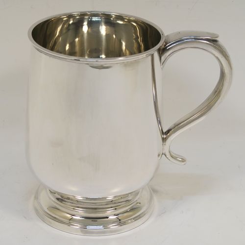 A handsome antique Sterling Silver pint tankard or mug, having a plain round body with straight sides and a tucked under belly, a scroll side-handle, and sitting on a pedestal foot. This elegant silver pint mug was made by Walker and Hall of Sheffield in 1917. The dimensions of this fine hand-made antique silver pint mug or tankard are height 13 cms (5 inches), diameter at top 8.5 cms (3.3 inches), and it weighs approx. 297g (9.6 troy ounces).  