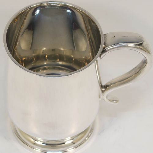 A handsome antique Sterling Silver pint tankard or mug, having a plain round body with straight sides and a tucked under belly, a scroll side-handle, and sitting on a pedestal foot. This elegant silver pint mug was made by Walker and Hall of Sheffield in 1917. The dimensions of this fine hand-made antique silver pint mug or tankard are height 13 cms (5 inches), diameter at top 8.5 cms (3.3 inches), and it weighs approx. 297g (9.6 troy ounces).  