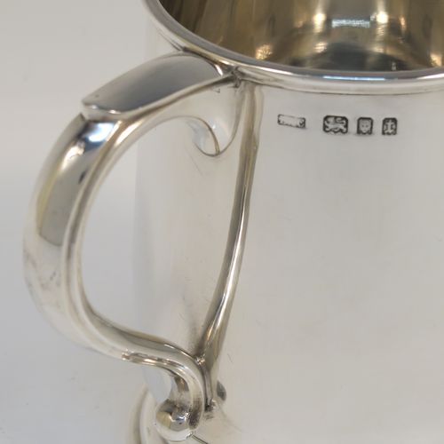 A heavy and very handsome Sterling Silver pint tankard or mug, having a plain round body with straight sides and a tucked under belly, a scroll side-handle, and sitting on a pedestal foot. This elegant silver pint mug was made by L. A. Crichton of London in 1934. The dimensions of this fine hand-made silver pint mug or tankard are height 12 cms (4.75 inches), diameter at top 9 cms (3.5 inches), and it weighs approx. 352g (11.3 troy ounces).   