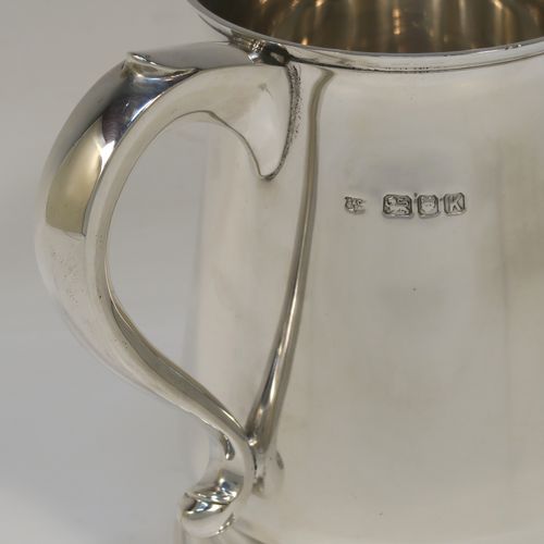 A handsome antique Sterling Silver pint tankard or mug, having a plain round body with straight sides and a tucked under belly, a plain scroll side-handle, and sitting on a pedestal foot. This elegant silver pint mug was made by Searle and Co. Ltd., of London in 1945. The dimensions of this fine hand-made antique silver pint mug or tankard are height 12.5 cms (5 inches), diameter at top 8.5 cms (3.3 inches), and it weighs approx. 360g (11.6 troy ounces).   