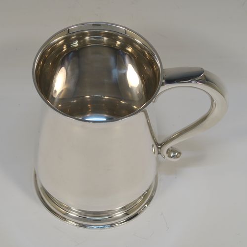 A handsome antique Sterling Silver pint tankard or mug, having a plain round body with straight sides and a tucked under belly, a plain scroll side-handle, and sitting on a pedestal foot. This elegant silver pint mug was made by Searle and Co. Ltd., of London in 1945. The dimensions of this fine hand-made antique silver pint mug or tankard are height 12.5 cms (5 inches), diameter at top 8.5 cms (3.3 inches), and it weighs approx. 360g (11.6 troy ounces).   