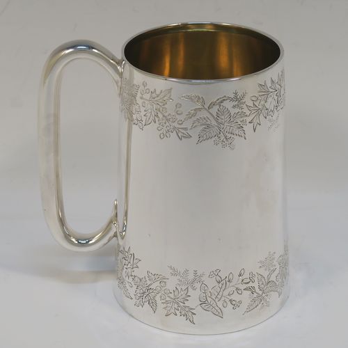 A very pretty Antique Victorian Sterling Silver pint mug or tankard, having a round body with straight tapering sides, with two bands of hand-engraved floral decoration, a gold-gilt interior, and a plain loop side-handle. This beautiful silver tankard or mug was made in Sheffield in 1878. The dimensions of this fine hand-made antique silver pint mug are height 13 cms (5 inches), diameter at top 7.5 cms (3 inches), and it weighs approx. 297g (9.6 troy ounces).   