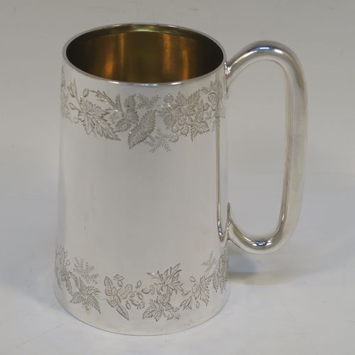 A very pretty Antique Victorian Sterling Silver pint mug or tankard, having a round body with straight tapering sides, with two bands of hand-engraved floral decoration, a gold-gilt interior, and a plain loop side-handle. This beautiful silver tankard or mug was made in Sheffield in 1878. The dimensions of this fine hand-made antique silver pint mug are height 13 cms (5 inches), diameter at top 7.5 cms (3 inches), and it weighs approx. 297g (9.6 troy ounces).   