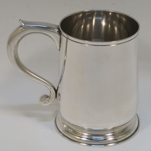 An elegant Sterling Silver pint tankard or mug, having a plain round body with straight sides and a tucked under belly, a plain scroll side-handle, and sitting on a pedestal foot. This handsome silver pint mug was made by Jones and Son of London in 1965. The dimensions of this fine hand-made silver pint mug or tankard are height 12 cms (4.75 inches), diameter at top 8 cms (3.25 inches), and it weighs approx. 355g (11.5 troy ounces).   