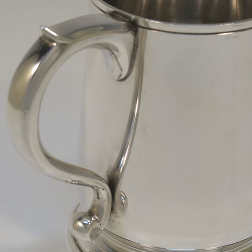 An elegant Sterling Silver pint tankard or mug, having a plain round body with straight sides and a tucked under belly, a plain scroll side-handle, and sitting on a pedestal foot. This handsome silver pint mug was made by Jones and Son of London in 1965. The dimensions of this fine hand-made silver pint mug or tankard are height 12 cms (4.75 inches), diameter at top 8 cms (3.25 inches), and it weighs approx. 355g (11.5 troy ounces).   