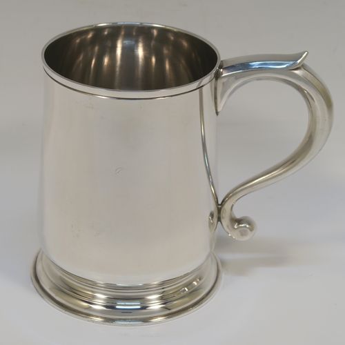 An elegant Sterling Silver pint tankard or mug, having a plain round body with straight sides and a tucked under belly, a plain scroll side-handle, and sitting on a pedestal foot. This handsome silver pint mug was made by Jones and Son of London in 1965. The dimensions of this fine hand-made silver pint mug or tankard are height 12 cms (4.75 inches), diameter at top 8 cms (3.25 inches), and it weighs approx. 355g (11.5 troy ounces).   