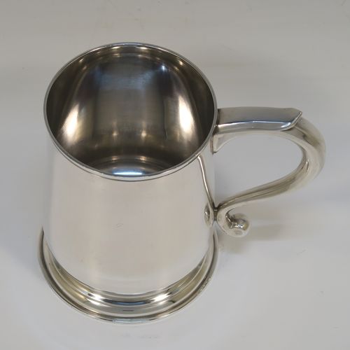 An elegant Sterling Silver pint tankard or mug, having a plain round body with straight sides and a tucked under belly, a plain scroll side-handle, and sitting on a pedestal foot. This handsome silver pint mug was made by Jones and Son of London in 1965. The dimensions of this fine hand-made silver pint mug or tankard are height 12 cms (4.75 inches), diameter at top 8 cms (3.25 inches), and it weighs approx. 355g (11.5 troy ounces).   