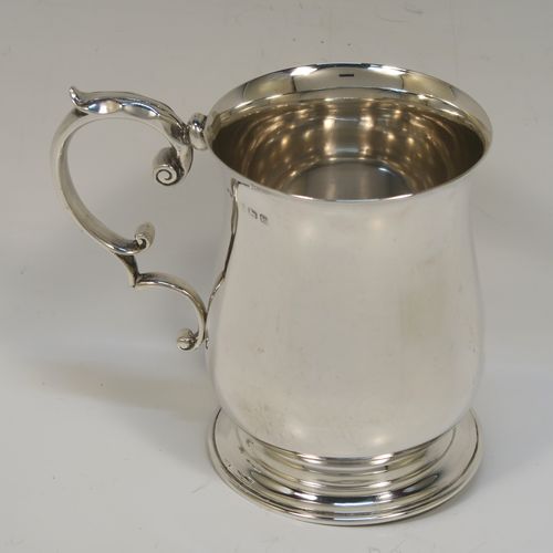 A very handsome Antique Sterling Silver half-pint tankard, having a plain round bellied body, a scroll handle with thumb-piece, and sitting on a pedestal foot. This elegant antique silver mug was made by Robert Chandler of London in 1921. The dimensions of this fine hand-made antique silver pint mug or tankard are height 10 cms (4 inches), diameter at top 7 cms (2.75 inches), and it weighs approx. 184g (5.9 troy ounces).   