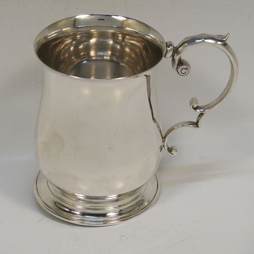 A very handsome Antique Sterling Silver half-pint tankard, having a plain round bellied body, a scroll handle with thumb-piece, and sitting on a pedestal foot. This elegant antique silver mug was made by Robert Chandler of London in 1921. The dimensions of this fine hand-made antique silver pint mug or tankard are height 10 cms (4 inches), diameter at top 7 cms (2.75 inches), and it weighs approx. 184g (5.9 troy ounces).   