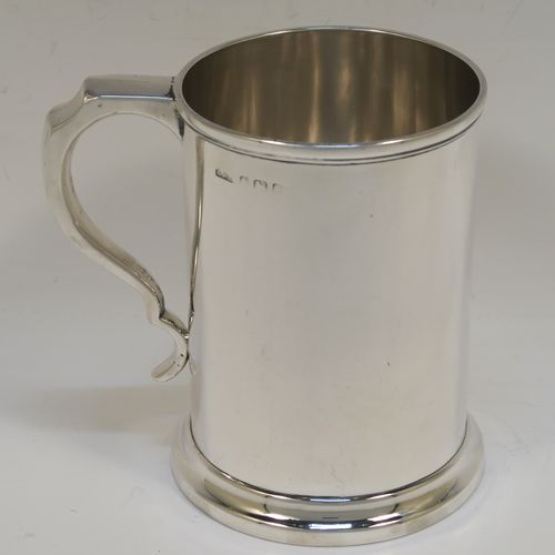 A very handsome Antique Edwardian Sterling Silver pint mug or tankard, in an early George I style, having a plain round straight-sided body with parallel sides, a plain scroll side-handle, and all sitting on a collet foot. This elegant antique silver pint tankard or mug was made by Henry Wilkinson of Birmingham in 1909. The dimensions of this fine hand-made silver tankard are height 12.5 cms (5 inches), diameter at top 9 cms (3.5 inches), and it weighs approx. 300g (9.7 troy ounces).   