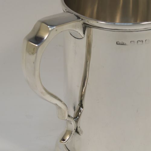 A very handsome Antique Edwardian Sterling Silver pint mug or tankard, in an early George I style, having a plain round straight-sided body with parallel sides, a plain scroll side-handle, and all sitting on a collet foot. This elegant antique silver pint tankard or mug was made by Henry Wilkinson of Birmingham in 1909. The dimensions of this fine hand-made silver tankard are height 12.5 cms (5 inches), diameter at top 9 cms (3.5 inches), and it weighs approx. 300g (9.7 troy ounces).   