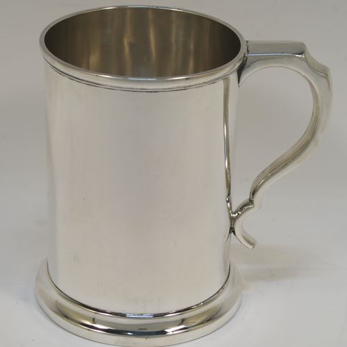 A very handsome Antique Edwardian Sterling Silver pint mug or tankard, in an early George I style, having a plain round straight-sided body with parallel sides, a plain scroll side-handle, and all sitting on a collet foot. This elegant antique silver pint tankard or mug was made by Henry Wilkinson of Birmingham in 1909. The dimensions of this fine hand-made silver tankard are height 12.5 cms (5 inches), diameter at top 9 cms (3.5 inches), and it weighs approx. 300g (9.7 troy ounces).   