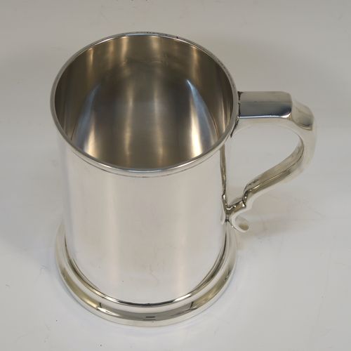 A very handsome Antique Edwardian Sterling Silver pint mug or tankard, in an early George I style, having a plain round straight-sided body with parallel sides, a plain scroll side-handle, and all sitting on a collet foot. This elegant antique silver pint tankard or mug was made by Henry Wilkinson of Birmingham in 1909. The dimensions of this fine hand-made silver tankard are height 12.5 cms (5 inches), diameter at top 9 cms (3.5 inches), and it weighs approx. 300g (9.7 troy ounces).   