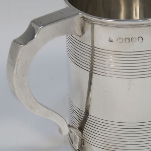 A very handsome Antique Georgian Sterling Silver pint tankard or mug, having a plain round straight-sided body with two bands of hand-chased reeded decoration and applied reeded borders, a square cross-section scroll handle, and sitting on a flat base. This elegant silver pint mug was made by Rebecca Emes and Edward Barnard I of London in 1810. The dimensions of this fine hand-made antique silver mug or tankard are height 11 cms (4.3 inches), length 13.5 cms (5.25 inches), and it weighs approx. 349g (11.25 troy ounces).   